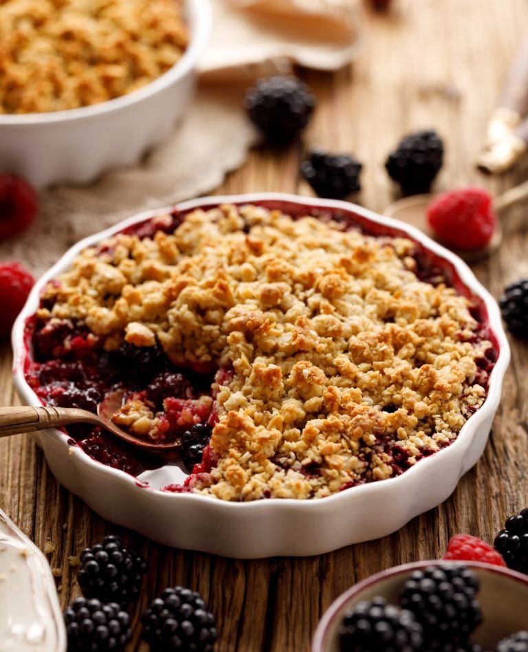berry pie with crisp topping in white dish on wooden tabletop