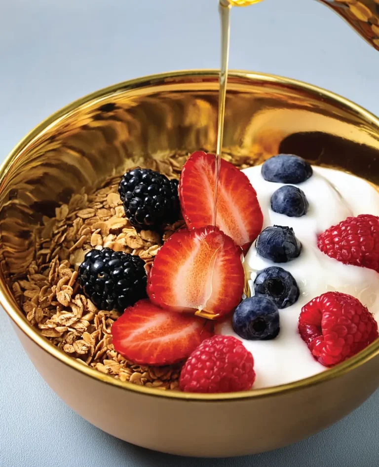 golden bowl with granola, berries, yogurt, and honey