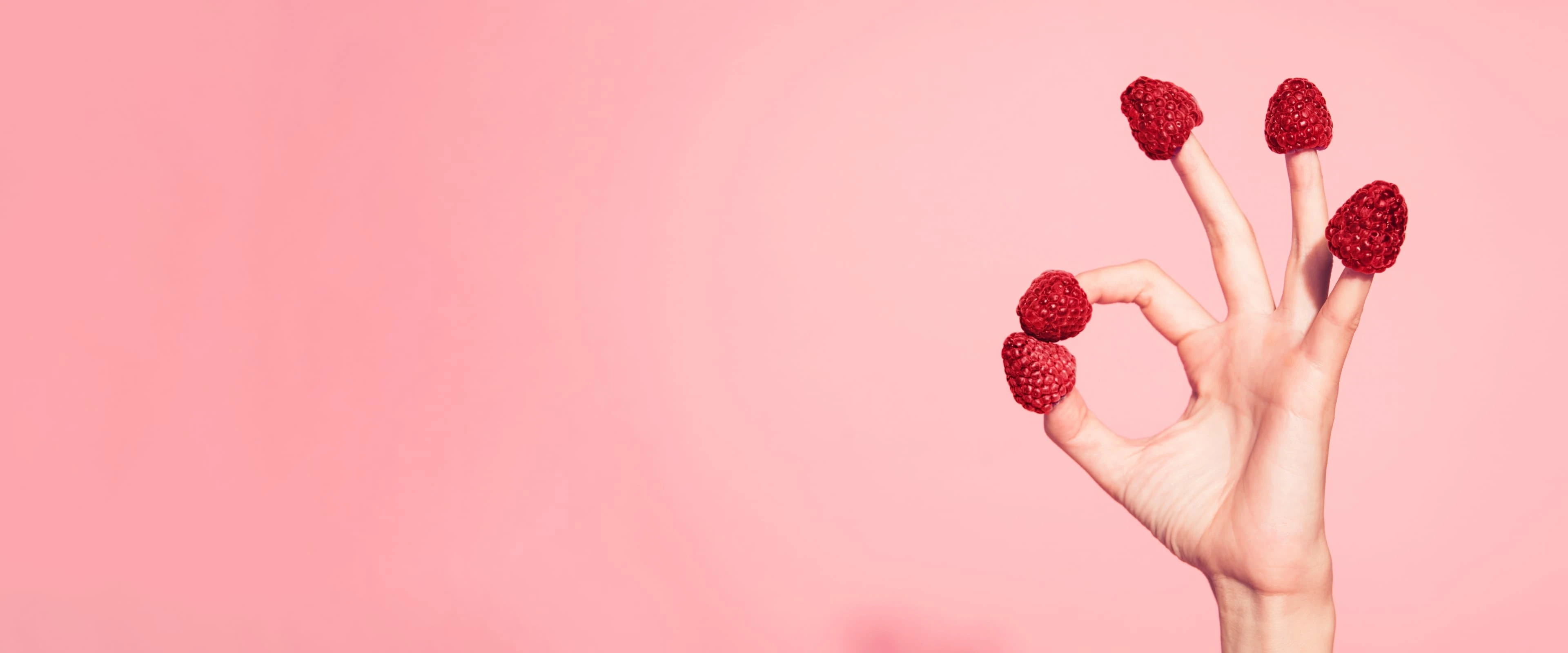 fingers with raspberries on the ends making an OK sign