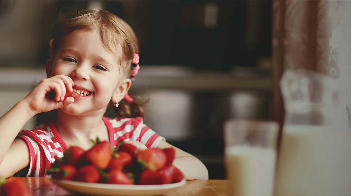 young girl smiling eating strawberries