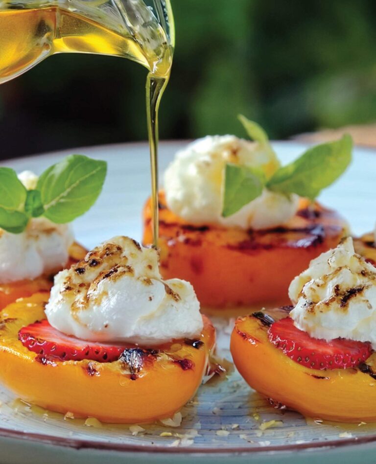 honey drizzling over grilled peaches with strawberry and cream topping