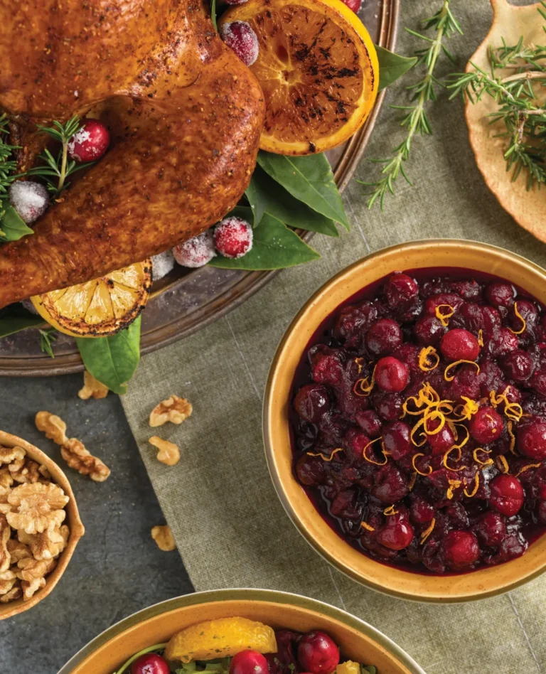 cooked turkey with roasted lemons, walnuts, and cranberry sauce on tabletop
