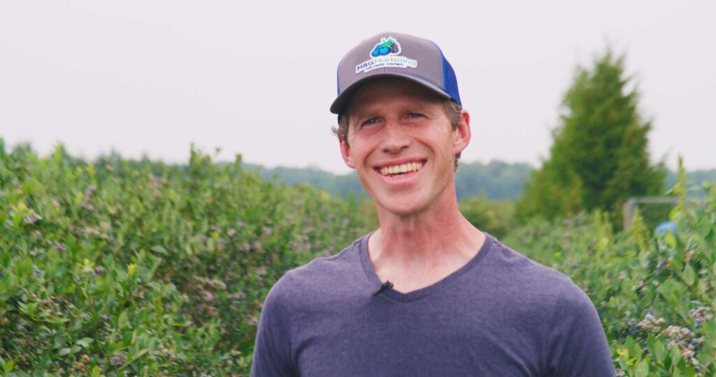 blueberry grower in field smiling
