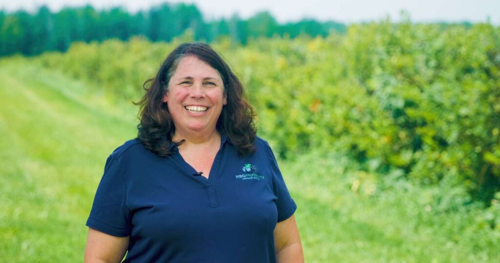 female blueberry grower in field smiling