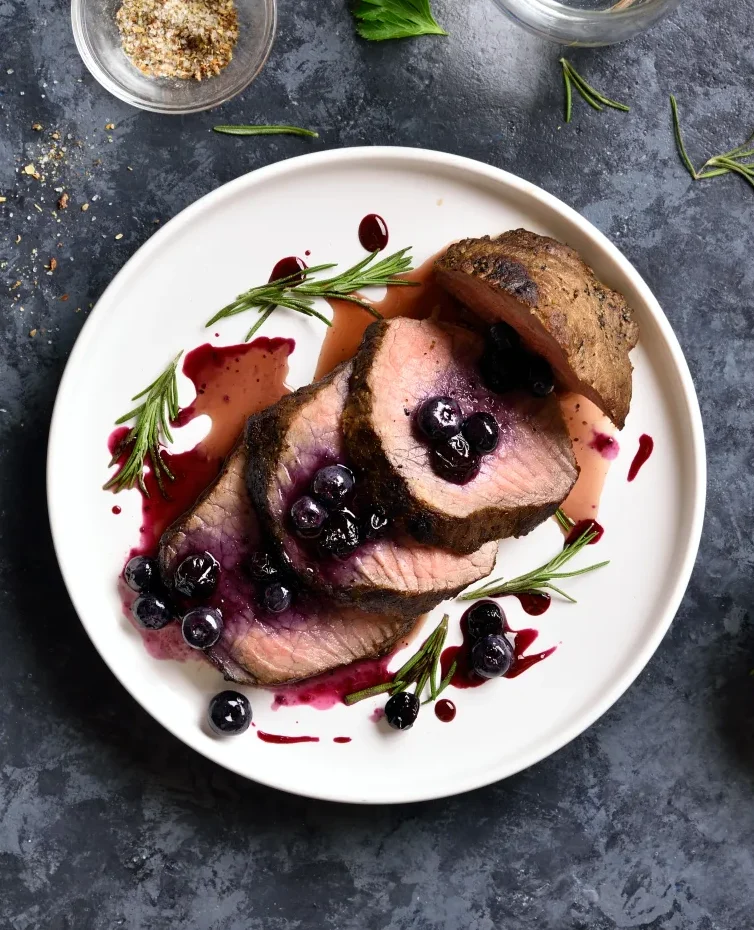 holiday roast with blueberry sauce on white plate